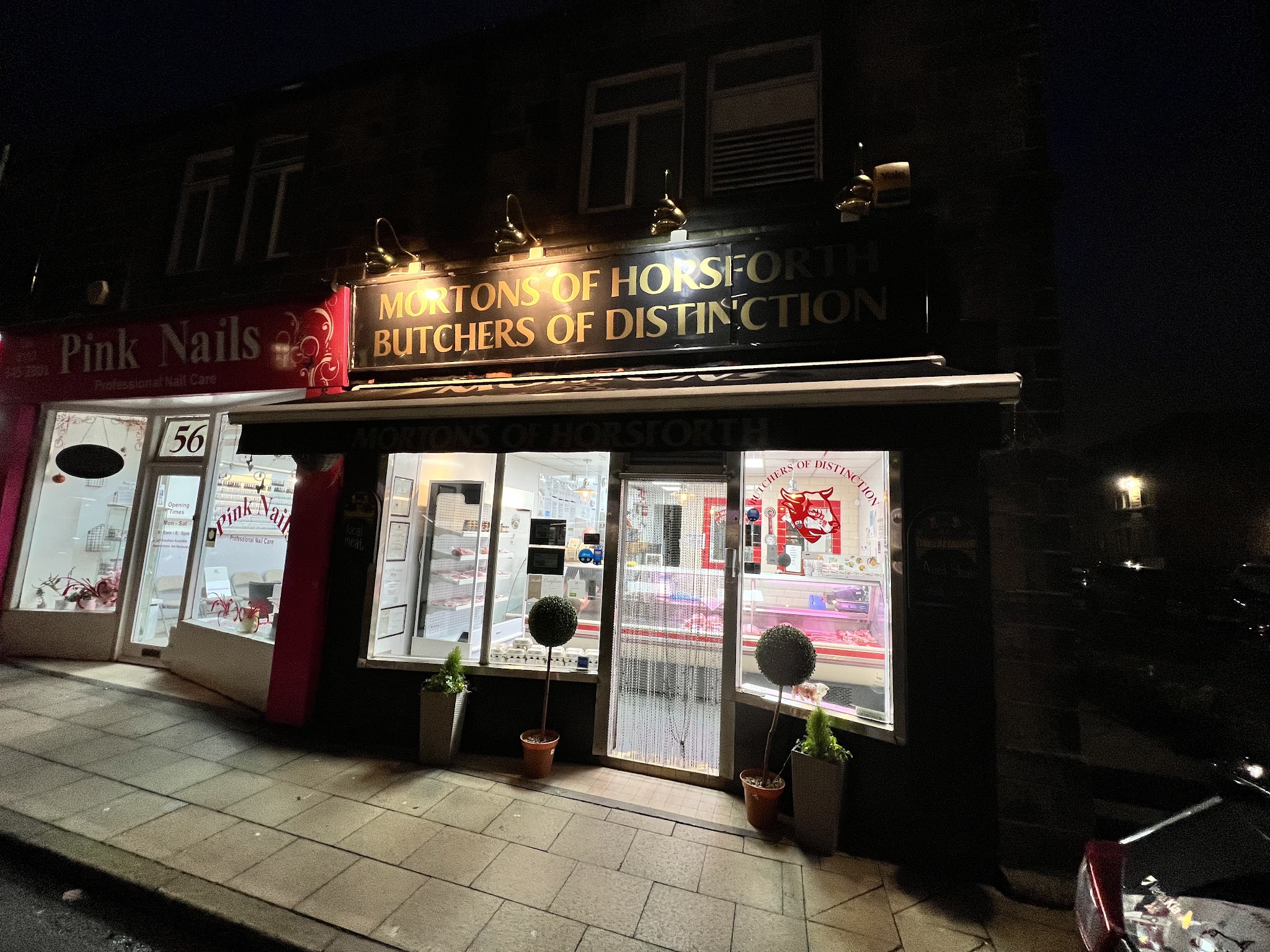 The illuminated gold Mortons of Horsforth sign above the butcher's shop on Town Street